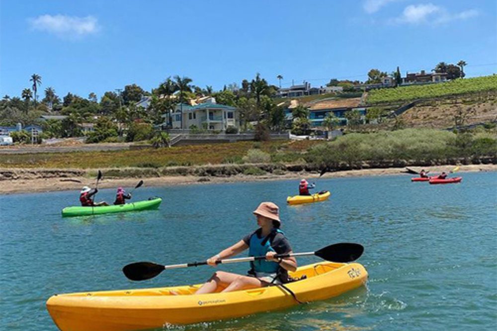 Family kayaking together at the Carlsbad Lagoon in North County San Diego