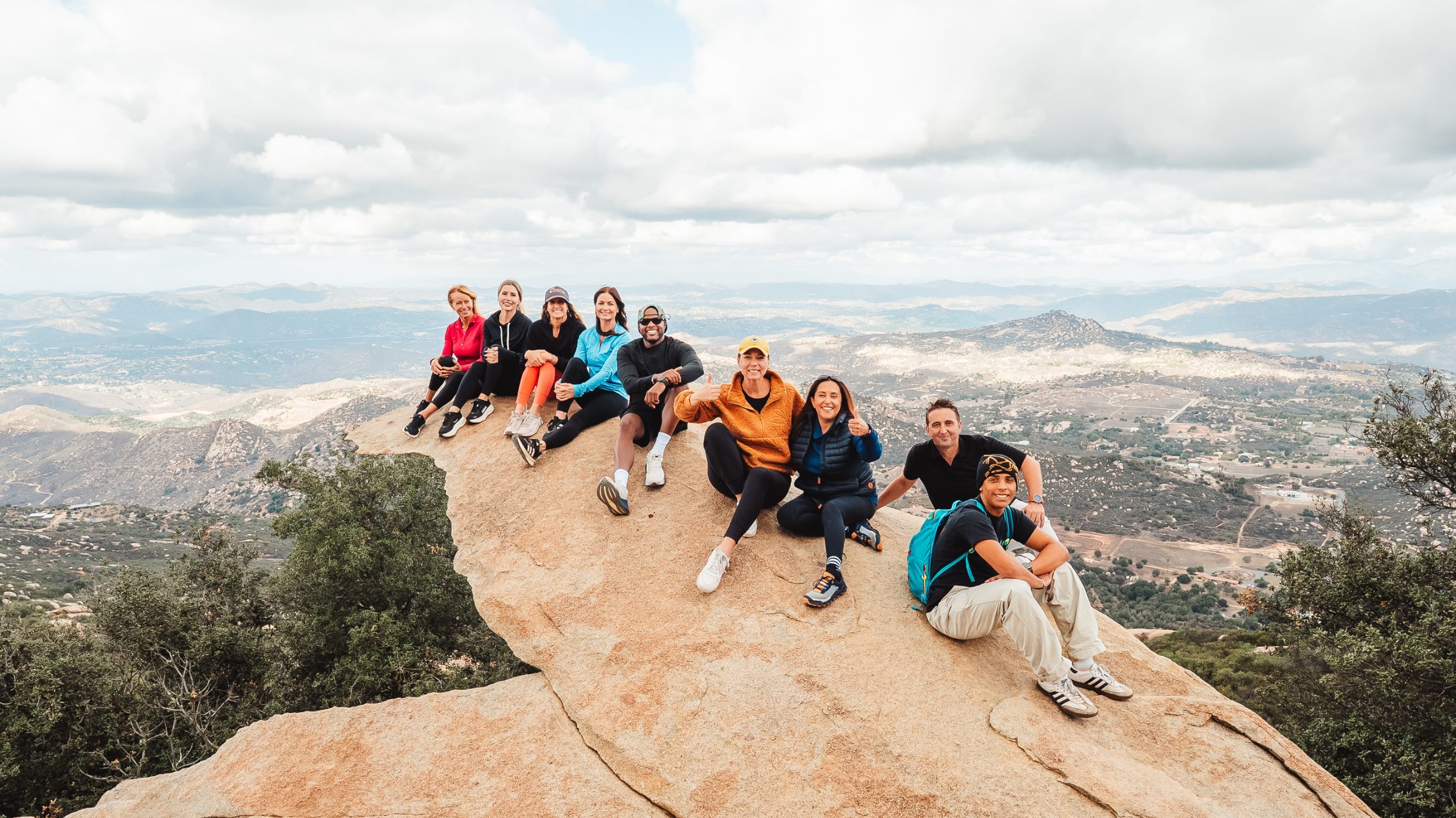 Karen Pietsch and team sitting on Potato Chip Rock overlooking North San Diego County